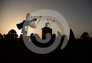 Space radar antenna on sunset. Silhouettes of satellite dishes or radio antennas against night sky. Space observatory or Air