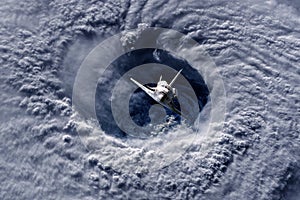 Space ship shuttle flying near earth from the hurricane and massive clouds in atmosphere, image made of NASA photos f