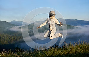 Space traveler jumping in the air in mountains.