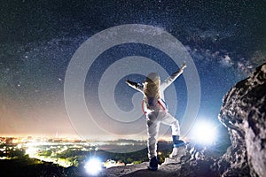 Spaceman standing under night starry sky and raising arms.