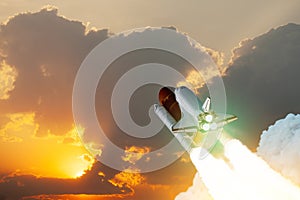 Spaceship lift off. Space shuttle with smoke and blast takes off into space on a background of sunset.