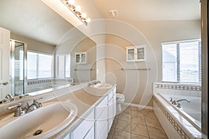 Spacious bathroom interior with windows and small wall cabinet on the front wall