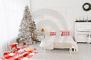 Spacious bright loft-style bedroom in white and red colors with a decorated Christmas tree