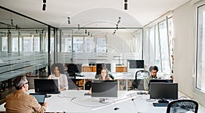 In a spacious and bright office, a diverse team is focused on individual tasks