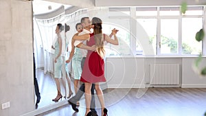 In spacious choreography studio, positive young adult man practicing elegant Viennese waltz with slender brunette in