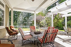 Spacious covered deck patio with table and red chairs.