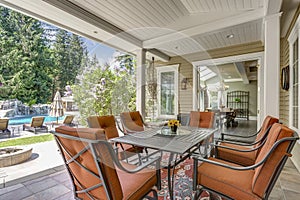 Spacious covered deck patio with table and red chairs.