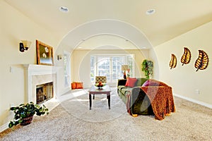 Spacious creamy tones interior of family room with green velvet sofa .