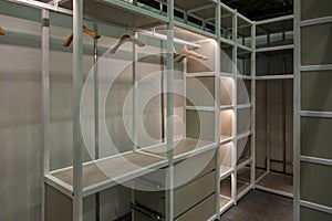 Spacious empty dressing room in white with shelves and wooden hangers. The overall look of the closet is neat and organized