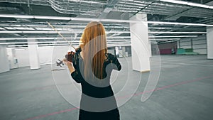 Spacious empty hall with a woman playing the violin