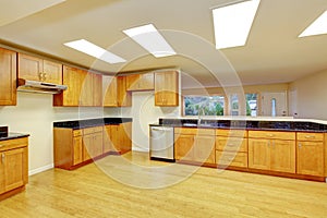 Spacious kitchen room with cabinets and black granite tops.