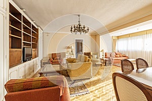 A spacious living room in a house with antique furniture with a yellow fabric lounge chair and other sofas, a white wooden