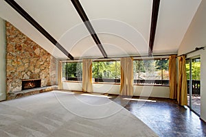 Spacious unfurnished living room interior with high vaulted ceiling and stone trim fireplace