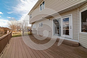 Spacious wooden deck of house overlooking the grassy backyard with playground