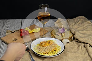 Spageti bolognese on a beautiful background next to stand a glass of white wine and clock.