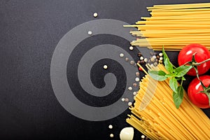 Spagetti, tomatoes and garlic on black background