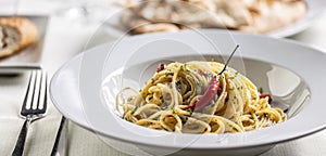 Spaghetti aglio e olio peperoncino with a hot fresh chilli served in a deep white plate photo