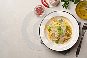 Spaghetti aglio e olio. Traditional Italian pasta with garlic, olive oil and chili peppers in plate on concrete background