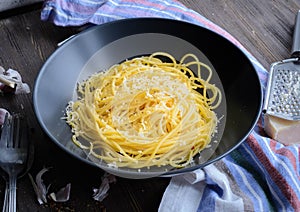 Spaghetti aglio olio on a plate with a small grater