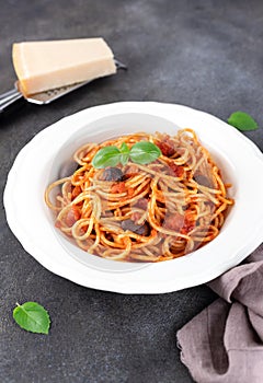 Spaghetti alla puttanesca or Neapolitan pasta on a gray background. Italian Cuisine.