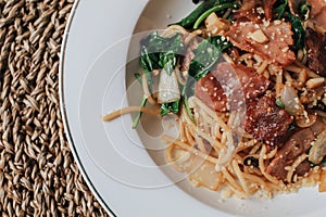 Spaghetti bacon, garlic, basil, dried chili pepper and cherry tomato on wood background.