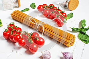 Spaghetti, basil and tomatoes isolated on white wooden table.