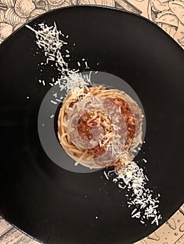 Spaghetti Bolognese . Black round plate.