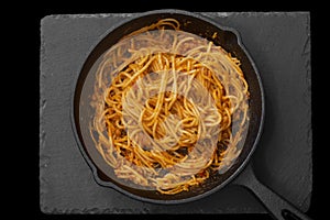 Spaghetti bolognese cooked in a cast iron frying pan.