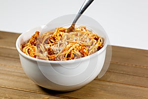 Spaghetti Bolognese in a deep white bowl on the wooden kitchen table waiting to be eaten