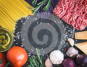 Spaghetti Bolognese ingredients on a dark stone background with