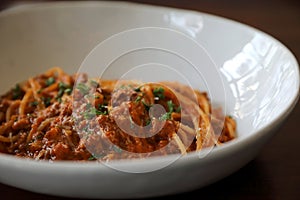 Spaghetti Bolognese with minced beef and tomato sauce garnished with parmesan cheese and basil , Italian food