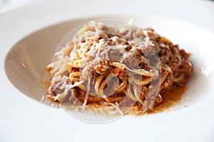 spaghetti Bolognese with minced beef and tomato sauce garnished with parmesan cheese and basil , Italian food