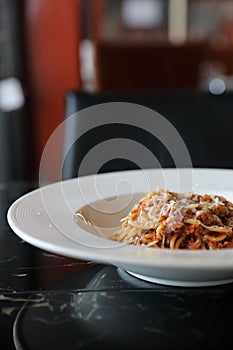 spaghetti Bolognese with minced beef and tomato sauce garnished with parmesan cheese and basil , Italian food