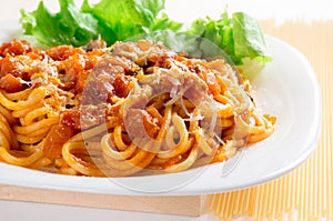 Spaghetti with bolognese and parmesan on a white plate