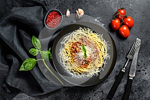 Spaghetti bolognese pasta with tomato and minced meat, parmesan cheese and basil. Black background. Top view