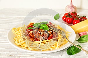 Spaghetti bolognese on a white plate with fork on white wooden table. healthy food