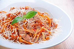 Spaghetti bolognese on white plate with tomato sauce and basi