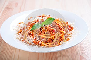 Spaghetti bolognese on white plate with tomato sauce and basil