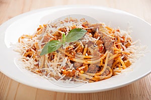 Spaghetti bolognese on white plate with tomato sauce and basil