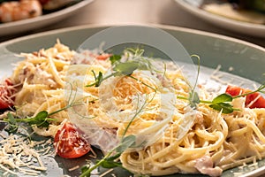 Spaghetti Carbonara with bacon and cheese on blue plate, close-up. Italian restaurant kitchen menu
