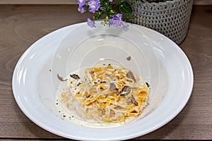 Spaghetti carbonara with cream sauce in a white plate on a wooden table