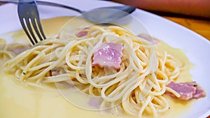 The spaghetti carbonara with fried cheese in a white plate on the table