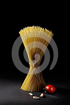 Spaghetti with cherry tomatoes and garlic on a black background