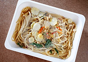 Spaghetti with chili pork basil leaf in food container.Top view.