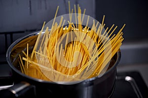 Spaghetti from durum wheat are cooked in a metal pot on the fire