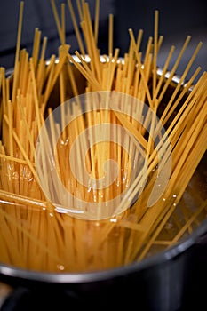 Spaghetti from durum wheat are cooked in a metal pot on the fire