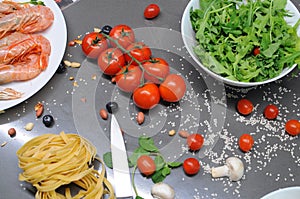 Spaghetti and fettuccine with ingredients for cooking pasta on wooden table with blank of round wooden kitchen board