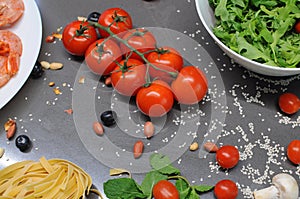 Spaghetti and fettuccine with ingredients for cooking pasta on wooden table with blank of round wooden kitchen board