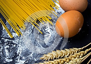 Spaghetti and flour and egg on black background