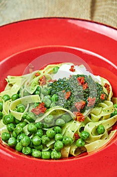 Spaghetti with fresh green peas. Gray textured background with beige fabric. Beautiful serving of dishes. Restaurant